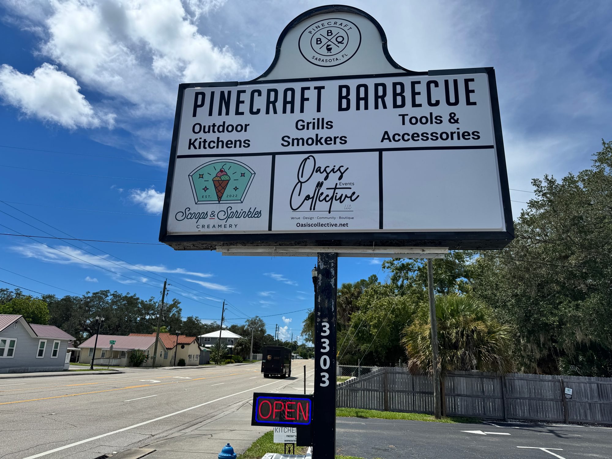Roadside pylon sign with Pinecraft Barbecue lettering, an Outdoor Kitchens panel, and the Sarasota logo.