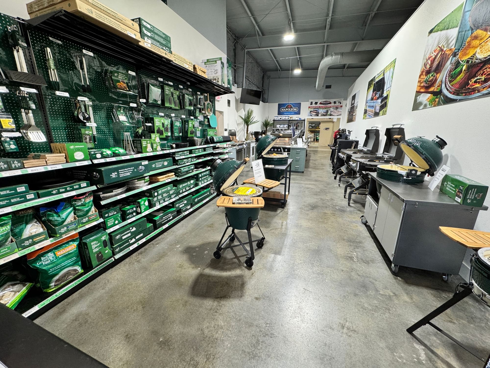 Big Green Egg aisle with ceramic cookers, tables, and an accessory wall.