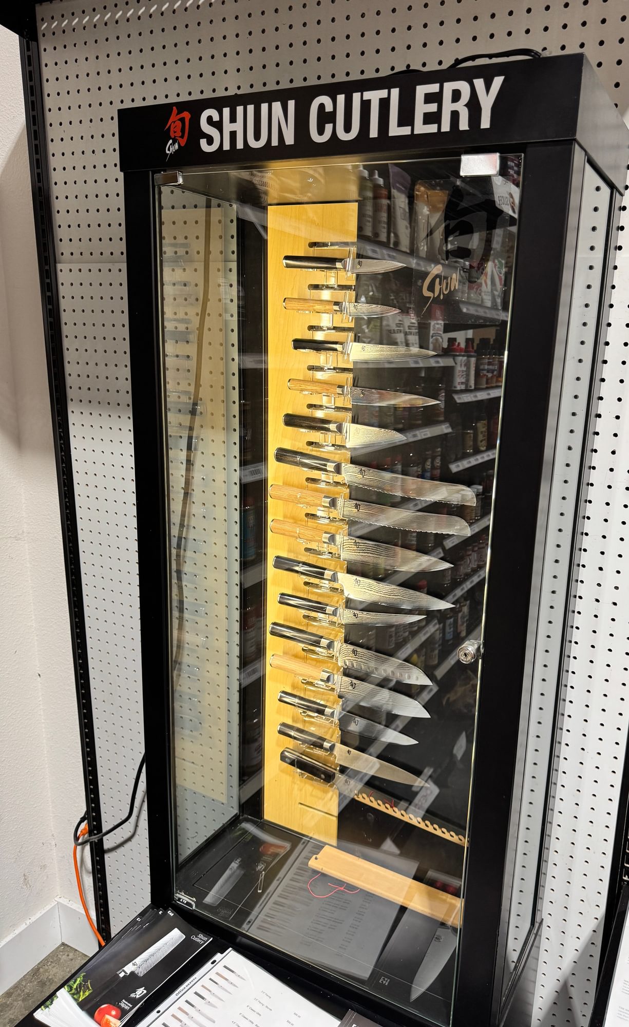 Lit Shun Cutlery case with knives against a pegboard wall.