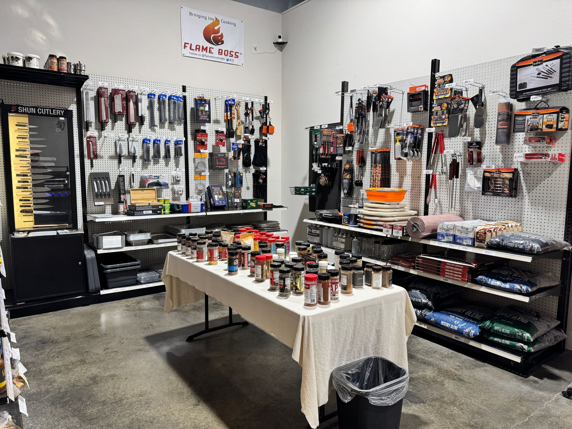 Accessory corner with grill tools, a seasoning table, and pellet bags.