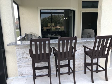 Three bar chairs beneath a covered patio.