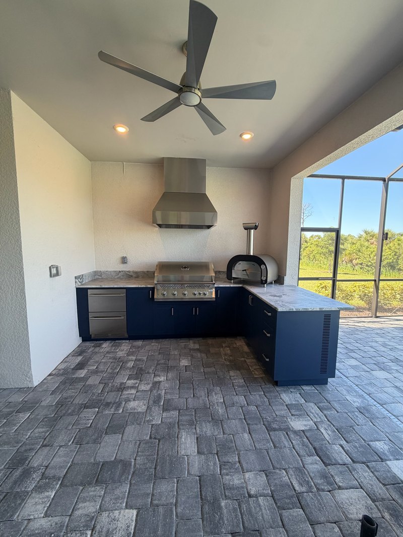 Blue L-shaped outdoor kitchen with a hood and oven.